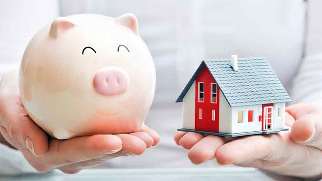 person holds piggy bank and model house